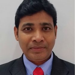 A man in a suit with a blue shirt and red tie stands confidently, embodying the precision akin to OpenRoads Designer, set against a plain background.